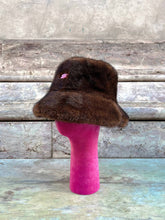 Carica l&#39;immagine nel visualizzatore di Gallery, Cappello da pescatore in eco pelliccia marrone firmato ely.b hats su un supporto rosa, ideale per l&#39;inverno, effetto visone